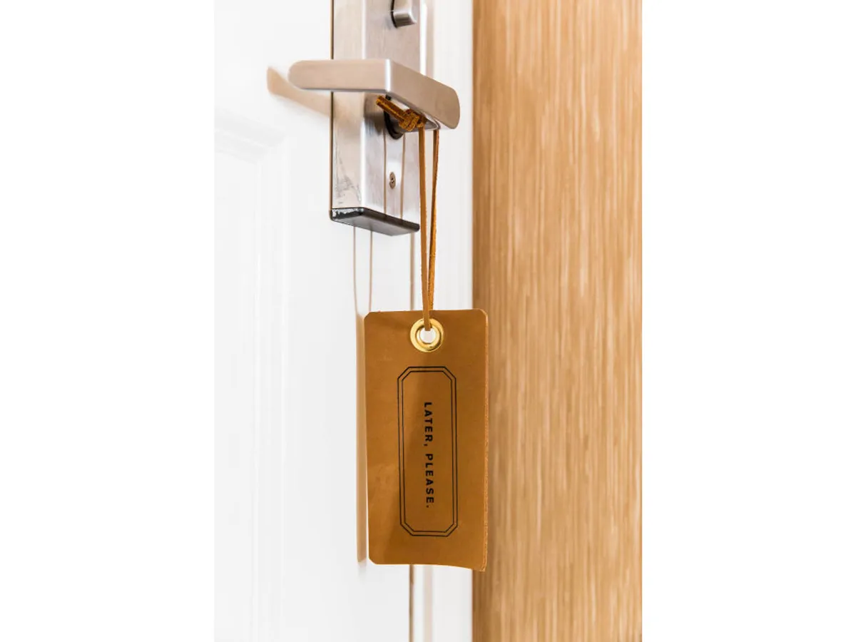 A close-up of a suite door with a visible door handle and door tag, evoking privacy and the personal retreat feeling. The perspective suggests an inviting entry into a restful private space, emphasizing intimacy and security.